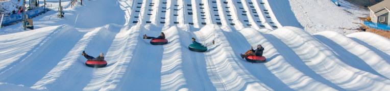 Four riders go down the snow tubing hill at Massanutten Resort
